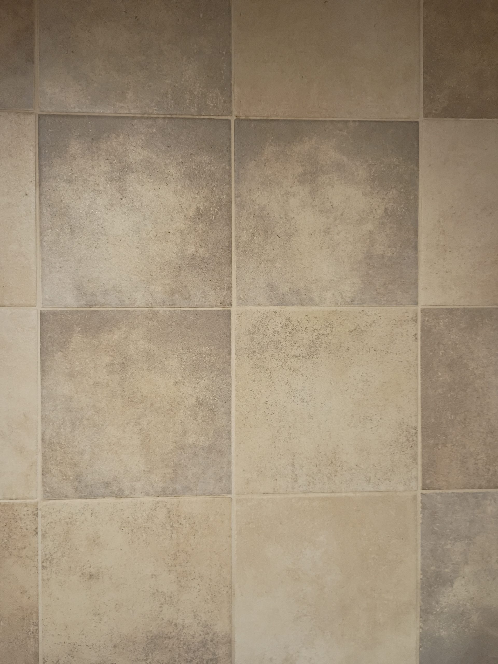 Tan tile floor laid in a diamond pattern beneath wooden kitchen cabinets.